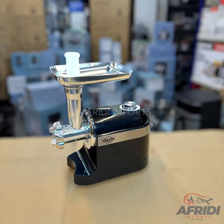 Black and silver electric meat grinder with a feeding tray and pusher.