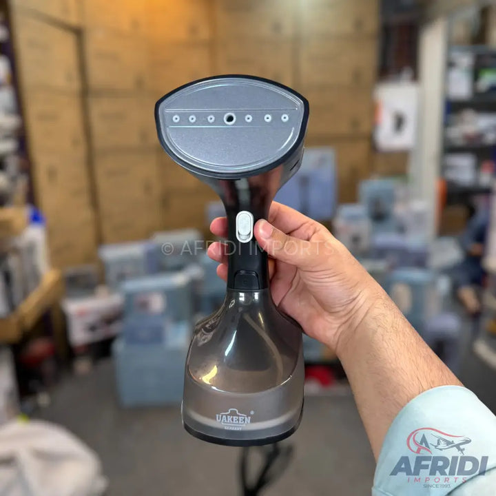 Dark grey handheld clothes steamer with a translucent water tank.