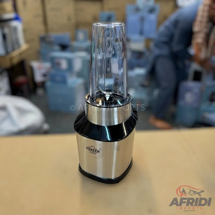A personal blender with a stainless steel base and a clear blending cup with a blade assembly.