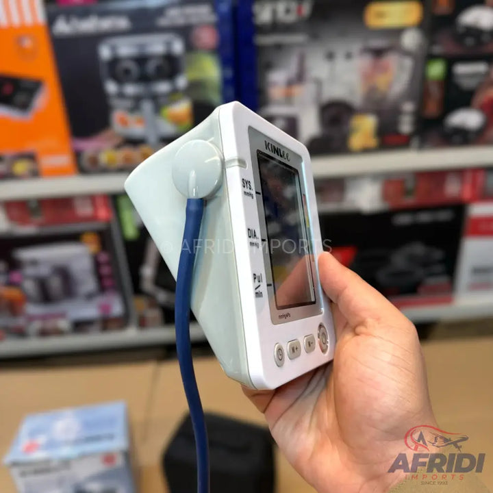 White and blue digital blood pressure monitor held in a hand.