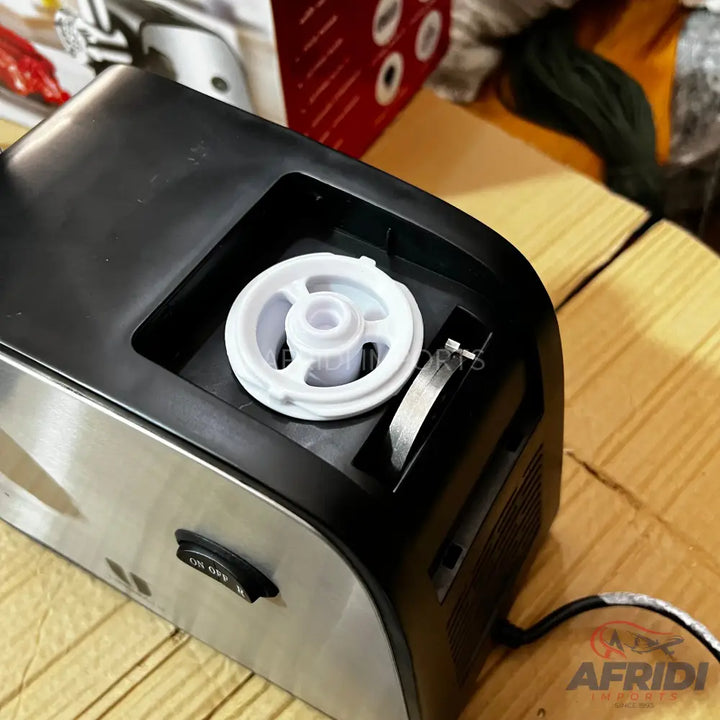 Silver and black countertop appliance with a white internal spool and an ’ON OFF’ switch.