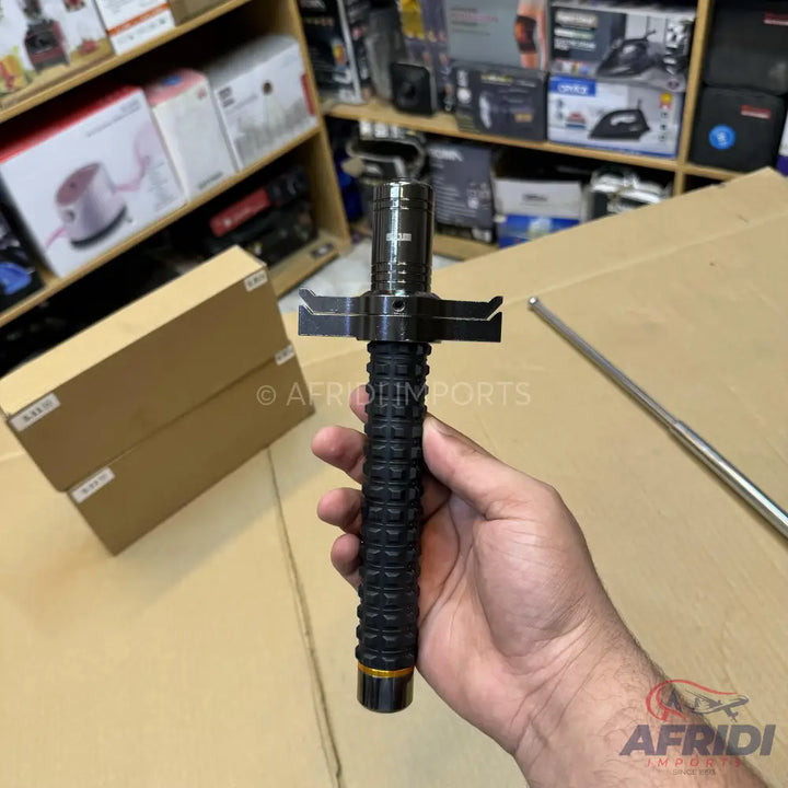 A black, textured, extendable baton with a silver crossguard.