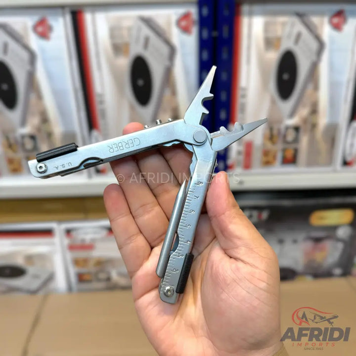 A stainless steel multi-tool with pliers, various blades, and a ruler, held open in a hand.