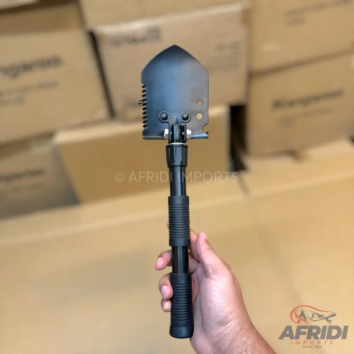 Black multi-tool folding shovel with a serrated edge and a collapsible handle.