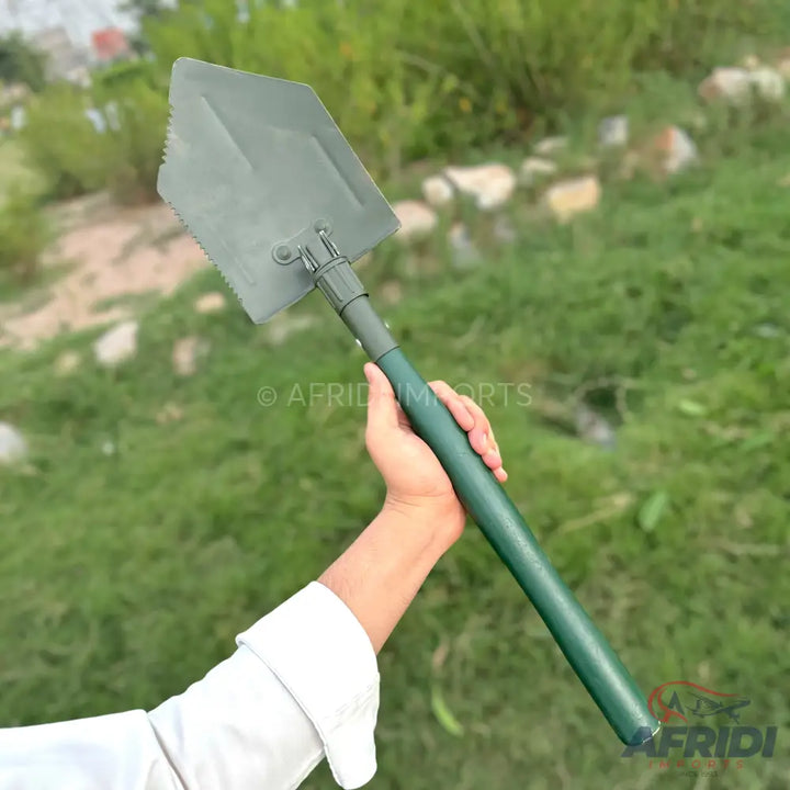 Green-handled, foldable military-style shovel with a serrated edge.