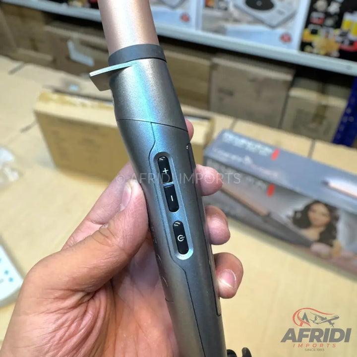 A gray and rose gold automatic curling iron with temperature and power controls.