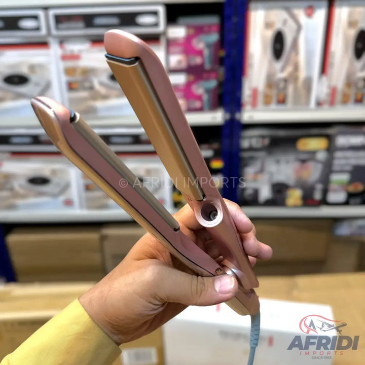 A rose gold hair straightener with ceramic plates.