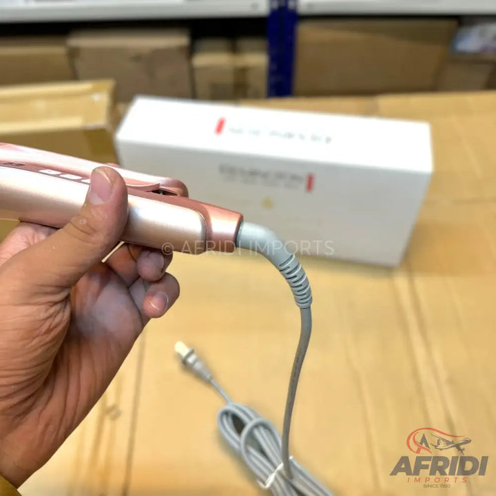 Rose gold hair styling tool with a grey power cord.