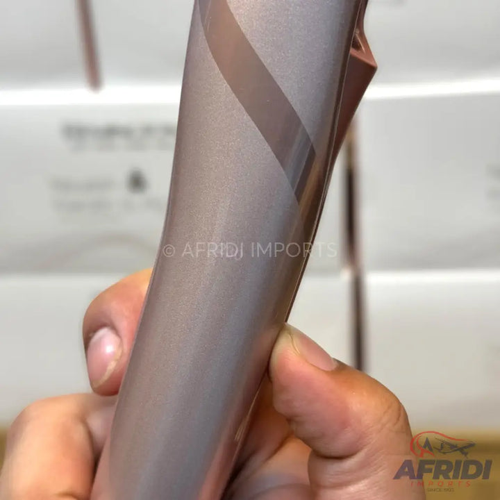 A metallic rose gold colored phone with a visible screen protector being peeled off.