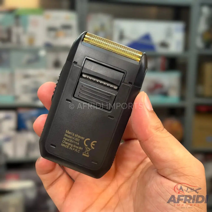 A black electric shaver with gold foil blades.