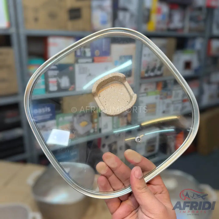 Square glass pot lid with a beige handle.
