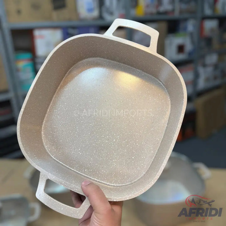 A light-colored square baking dish with two handles and a speckled non-stick coating.