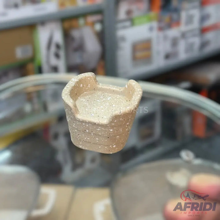 A speckled, light-colored ceramic pot, shaped like a mini armchair, designed for planting small succulents or herbs.