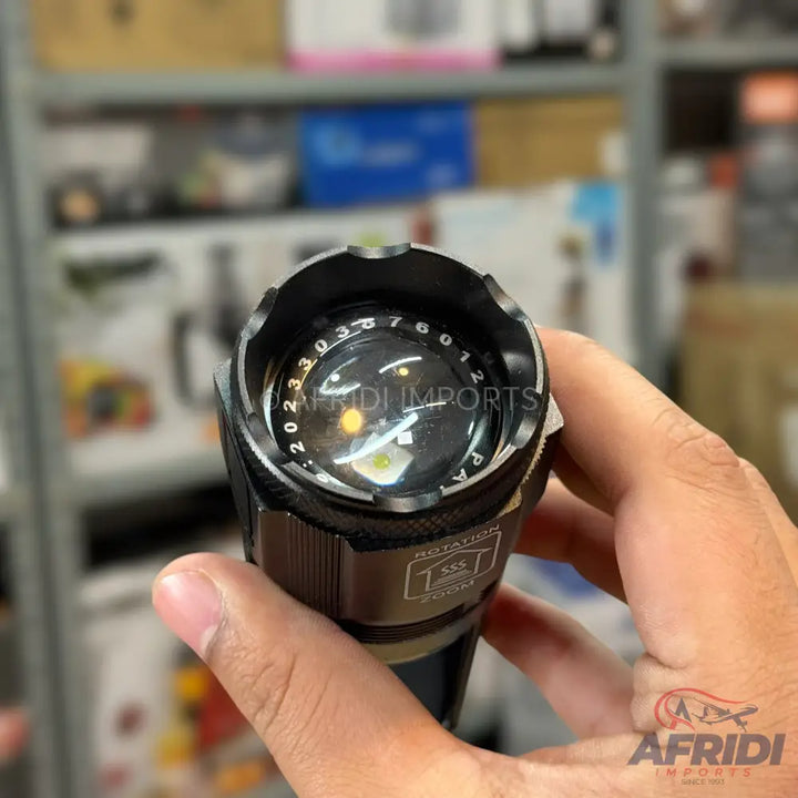 A black tactical flashlight with a zoom function and numbered bezel.
