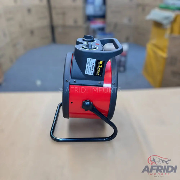 Red and black portable industrial fan with a handle and control knob.