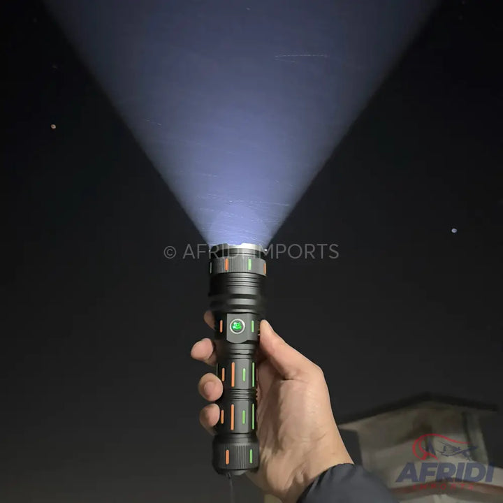 Hand holding a black flashlight with a bright white beam.
