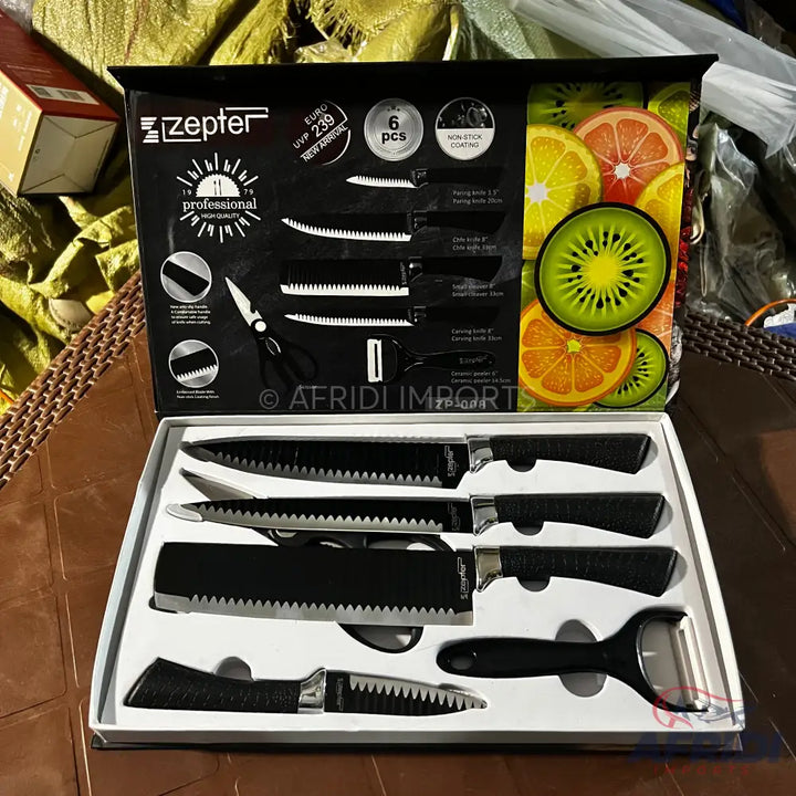 A six-piece knife set with black serrated blades and handles, including a peeler and scissors, in a white display box.