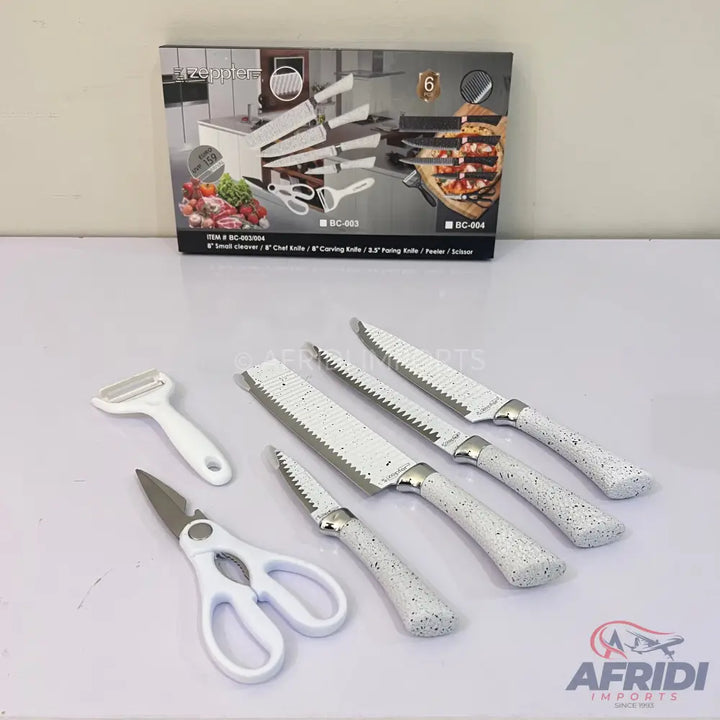 White-handled kitchen knife set with a peeler and scissors.
