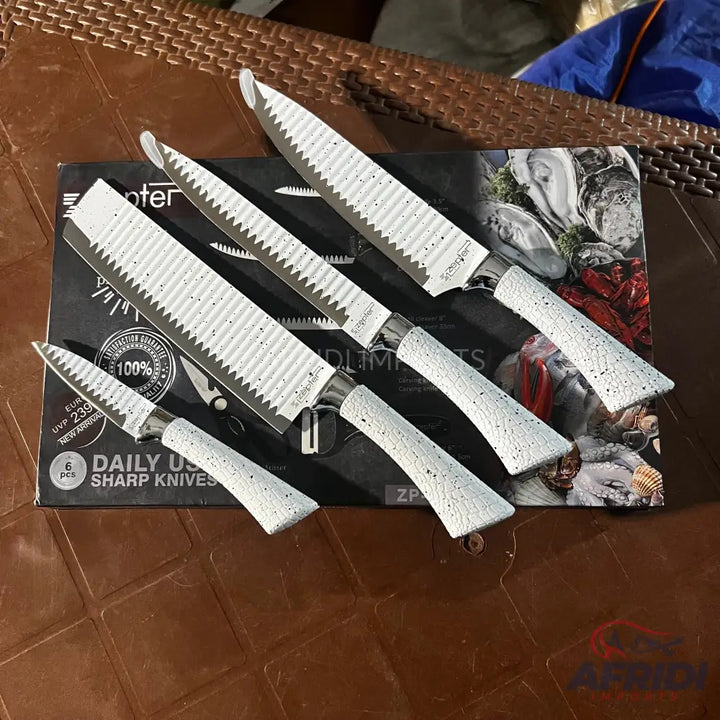 A set of five white-handled, serrated kitchen knives.